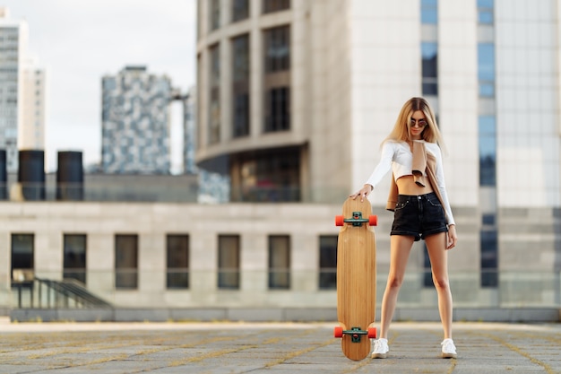 Jonge vrouw rijdt een longboard door de stad. Hoge kwaliteit foto