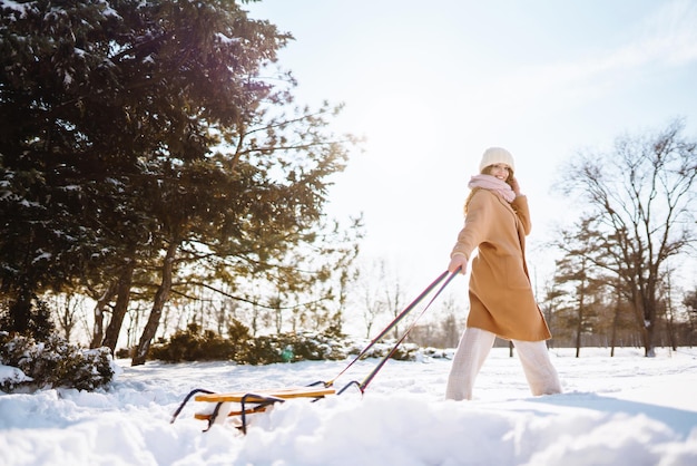 Jonge vrouw rolt op een slee in het besneeuwde winterbos Natuurvakanties rust reisconcept