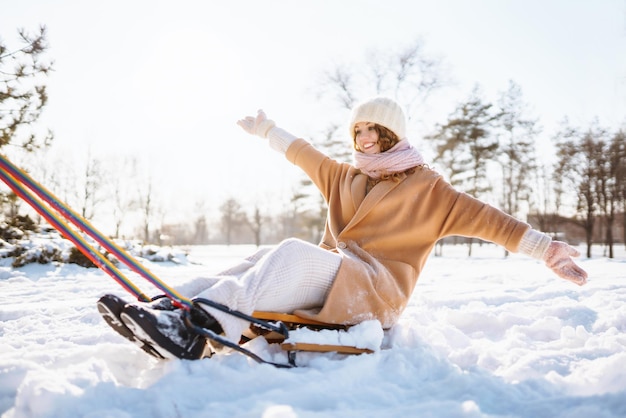 Jonge vrouw rolt op een slee in het besneeuwde winterbos Natuurvakanties rust reisconcept