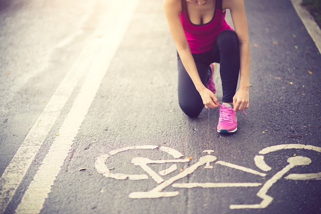 Foto jonge vrouw runner gelijkmakende schoenveter op landweg