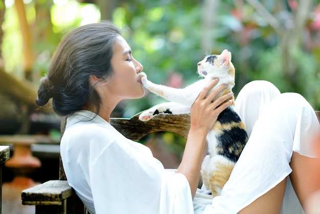 Jonge vrouw rust met een kat op de fauteuil in de tuin