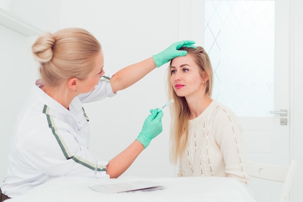 Jonge vrouw schoonheidsspecialiste praten met een jonge blonde vrouw over nieuwe gezichtsverzorging procedures Profe