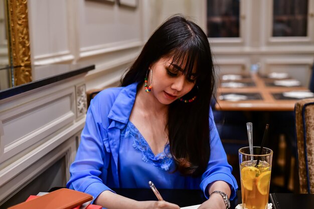 Jonge vrouw schrijft in boek door te drinken op tafel
