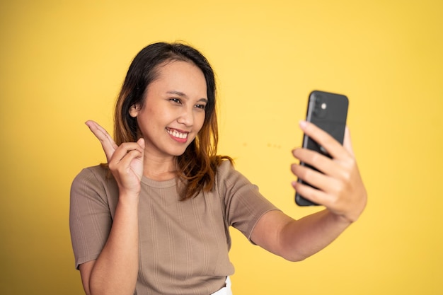 Jonge vrouw selfie met behulp van mobiele telefooncamera met v-teken