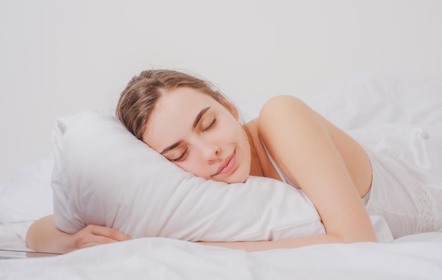 Foto jonge vrouw slaapt goed in bed knuffelend zacht wit kussen meisje rust goede nachtrust vrouw slaap