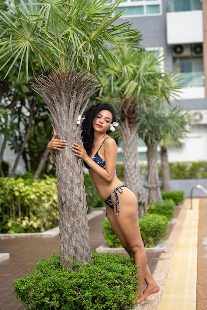Jonge vrouw slank gebruind lichaam in bikini op Palm leavers positieve roodharige vrouw met schone huid en natuurlijke schoonheid permanent achter tropische blad zomervakantie huidverzorging concept bikini in de natuur