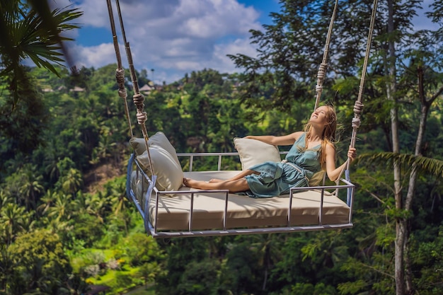 Jonge vrouw slingert in het jungle-regenwoud van het eiland Bali, Indonesië Schommel in de tropen Schommeltrend van Bali