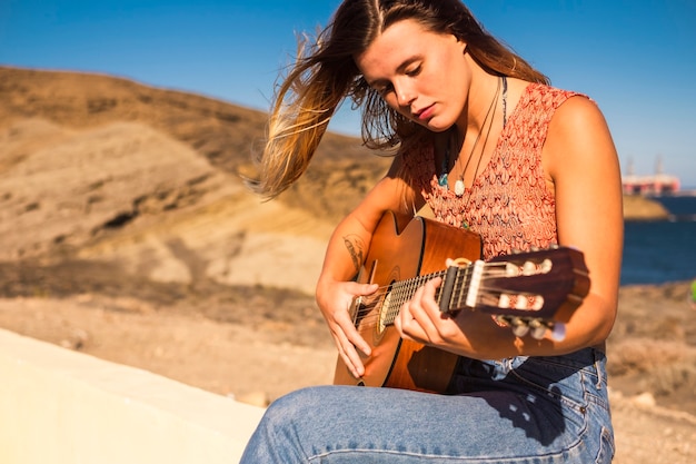 jonge vrouw speelt akoestische gitaar buiten.