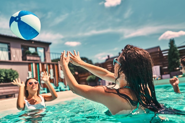 Jonge vrouw speelt in het zwembad met een strandbal Zijaanzicht