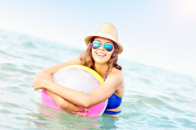 Jonge vrouw speelt met een bal in de zee playing