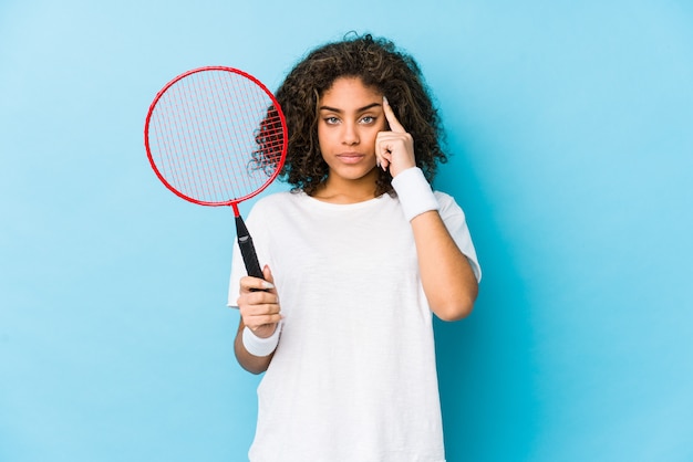 Jonge vrouw spelen badminton wijzende tempel met vinger, denken, gericht op een taak