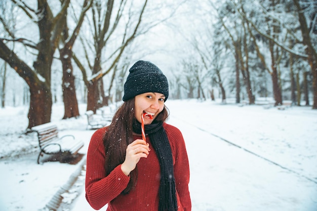 Jonge vrouw spelen in gesneeuwd stadspark. kerst snoep concept