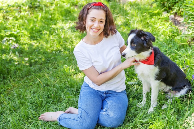 Jonge vrouw spelen met schattige puppy hondje border collie in zomertuin of stadspark buiten