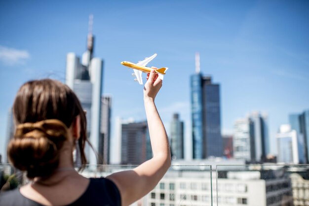 Jonge vrouw spelen met speelgoed vliegtuig op de achtergrond van de moderne stadsgezicht in Frankfurt. Luchtvervoersconcept in Frankfurt. Frankfurt heeft een zeer grote luchtvaartverbinding in Europa