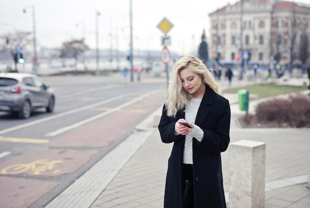 Jonge vrouw spreekt en schrijft met de telefoon op straat
