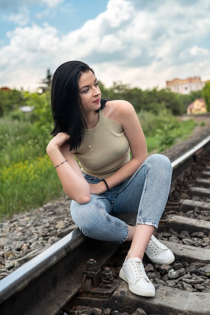 Jonge vrouw staande op een spoorlijn, reizen met de trein in de zomervakantie.