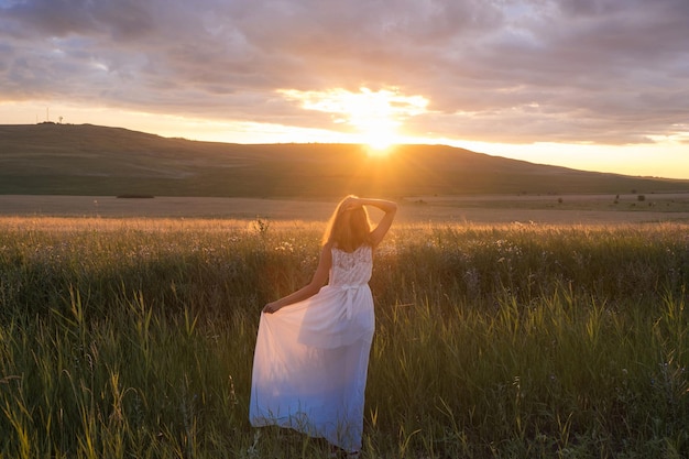 Jonge vrouw staande op een tarweveld met zonsopgang op de achtergrond