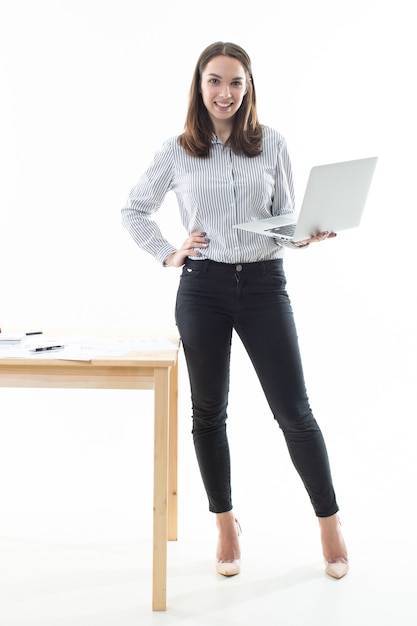 Jonge vrouw staat naast de tafel en werkt op een computer
