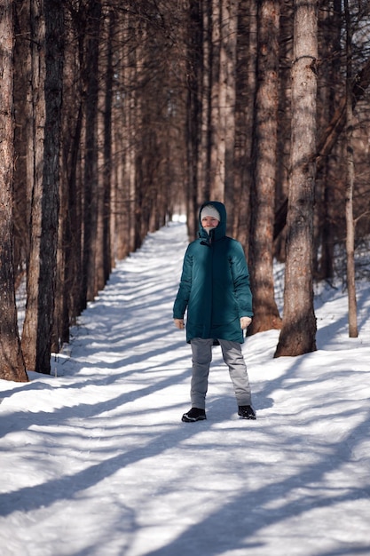 Jonge vrouw staat op de weg tussen bomen Kaukasische vrouw loopt op zonnige ijzige dag in het bos na zware...