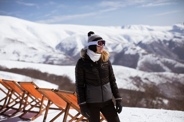 Jonge vrouw staat op een besneeuwde berghelling in haar skipak