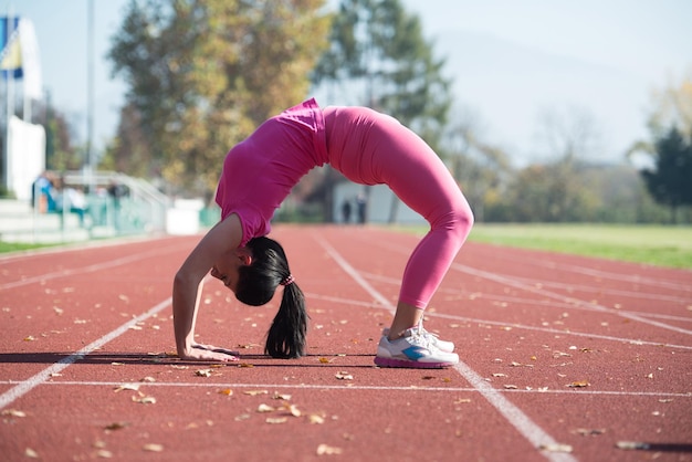 Jonge vrouw strekt zich uit op de vloer in het stadspark en traint voor uithoudingsvermogen Fitness gezonde levensstijl Concept buiten