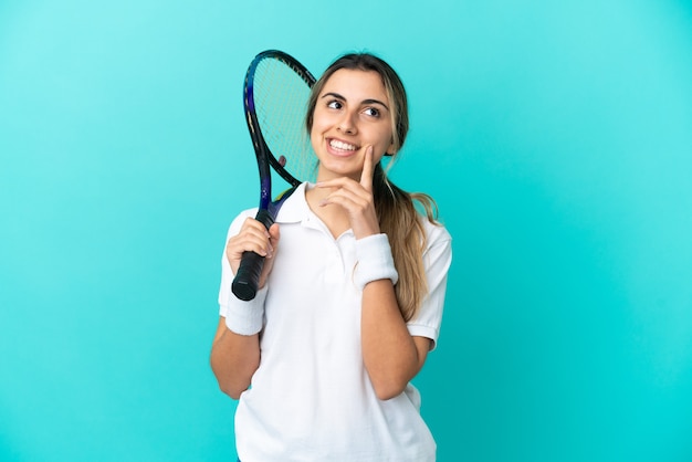 Jonge vrouw tennisser geïsoleerd op blauwe achtergrond een idee denken tijdens het opzoeken