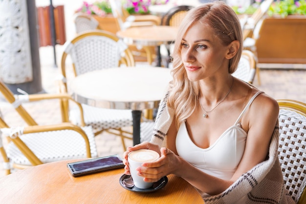 Jonge vrouw terwijl u ontspant in café aan tafel op straat gelukkige blanke vrouw