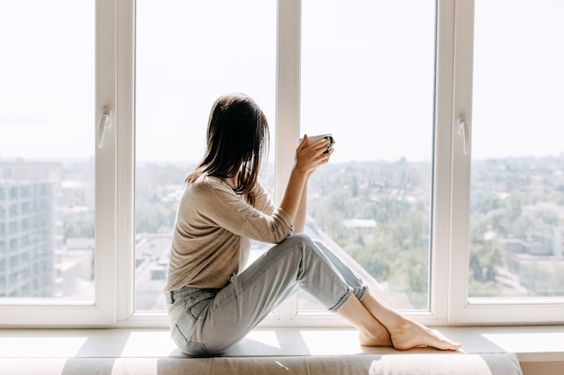 Jonge vrouw thuis koffie drinken