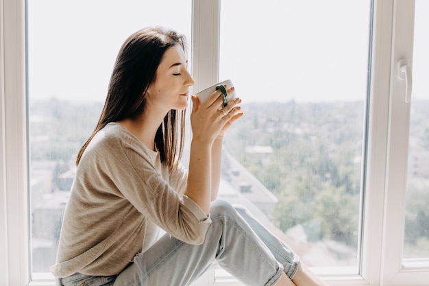 Jonge vrouw thuis koffie drinken