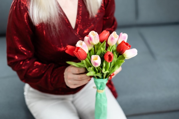 Jonge vrouw thuis moederdag concept met tulpen boeket glimlachend close-up.