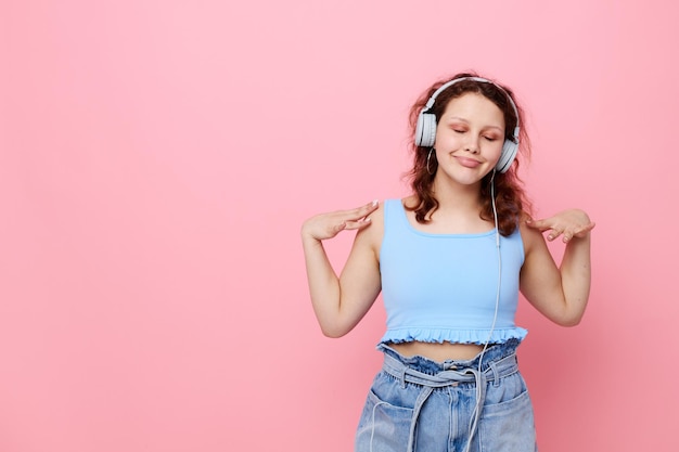 Jonge vrouw tiener draagt koptelefoon muziek entertainment roze achtergrond ongewijzigd Hoge kwaliteit foto