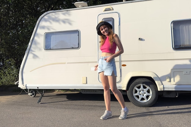 Jonge vrouw tiener meisje staat in de buurt van motorhome trailer camping concept