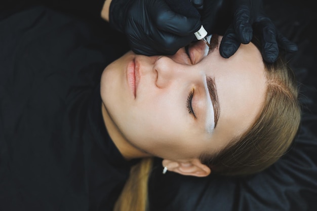 Jonge vrouw tijdens professionele wenkbrauw mapping procedure voor permanente make-up