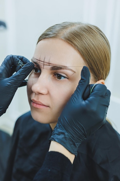 Jonge vrouw tijdens professionele wenkbrauw mapping procedure voor permanente make-up