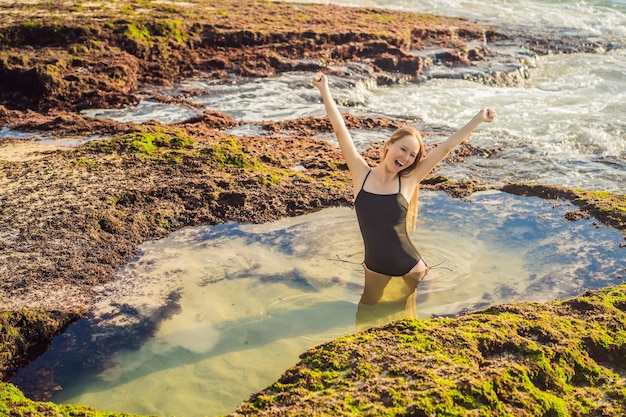 Foto jonge vrouw toerist op pantai tegal wangi beach zittend in een bad van zeewater bali island indonesië bali travel concept