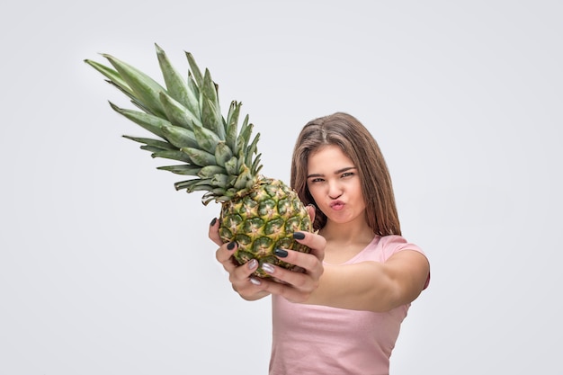 Jonge vrouw toont ananas uit handen