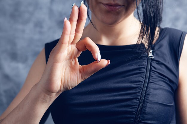 Jonge vrouw toont ok op grijze achtergrond