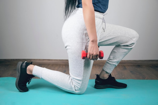 Jonge vrouw trainen met halters op de mat