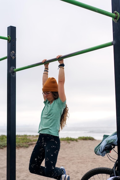 Jonge vrouw training op pull-up bar buiten op het strand