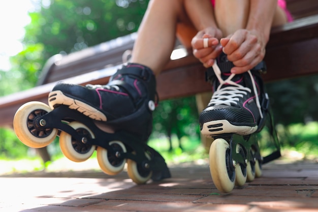 Foto jonge vrouw trekt rolschaatsen aan in parksport en wandelconcept