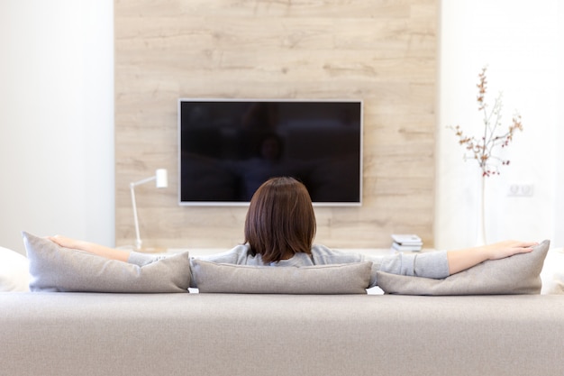 Jonge vrouw tv kijken in de kamer