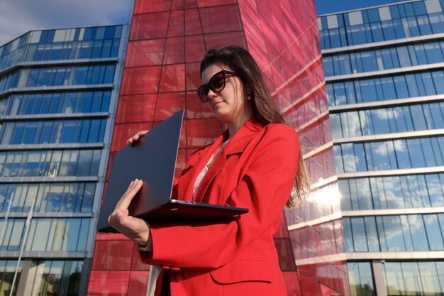 Jonge vrouw typt op een laptop voor een kantoorgebouw