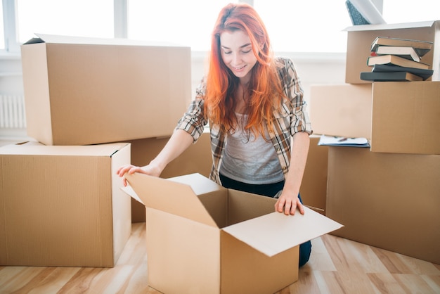 Jonge vrouw uitpakken van kartonnen dozen, Inwijdingsfeest. Verhuizing naar nieuw huis