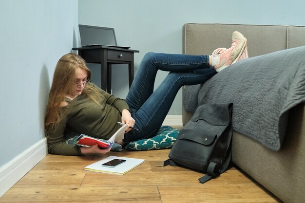 Jonge vrouw universiteitsstudent om thuis te zitten op de vloer en studeren met behulp van boeken