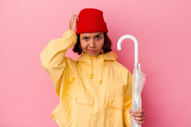 Foto jonge vrouw van gemengd ras met een paraplu geïsoleerd op een roze achtergrond die geschokt is, ze herinnert zich een belangrijke vergadering.