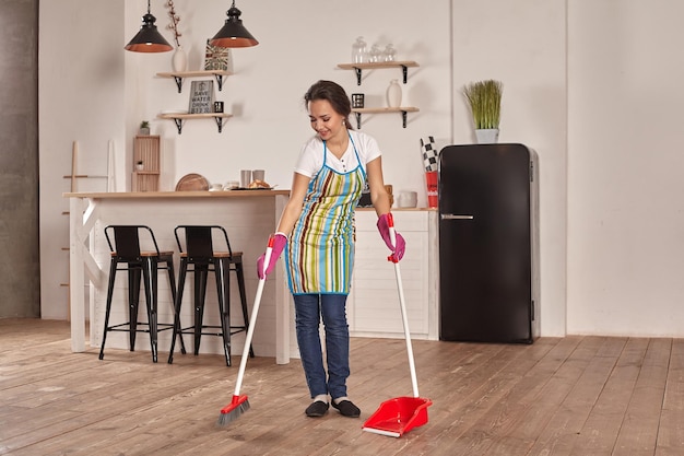 Jonge vrouw veegt de vloer in de keuken