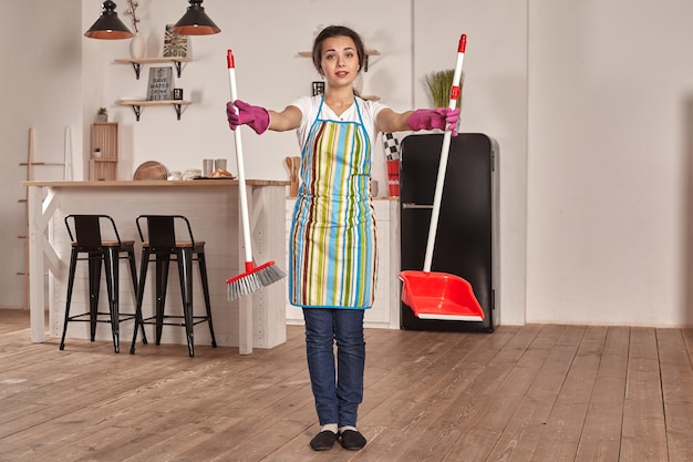 Jonge vrouw veegt de vloer in de keuken