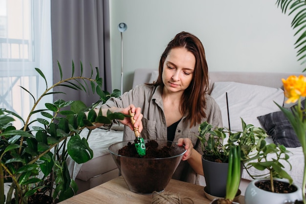 Jonge vrouw verplant voorjaarsmest voor kamerplanten voor thuisbloemen