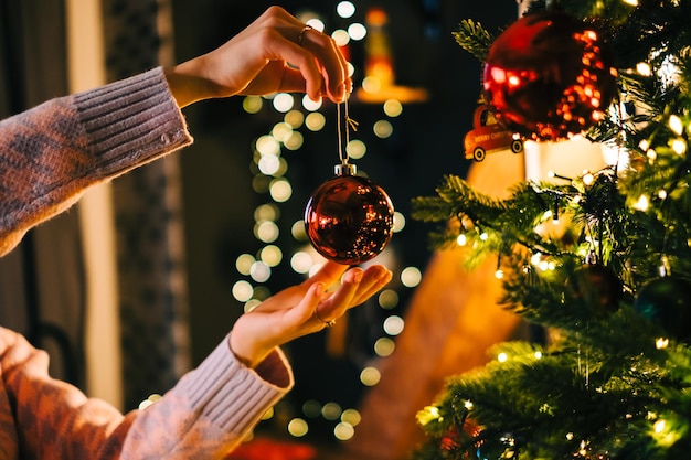 Jonge vrouw versiert de kerstboom met speelgoed. Voorbereiden op de feestdagen