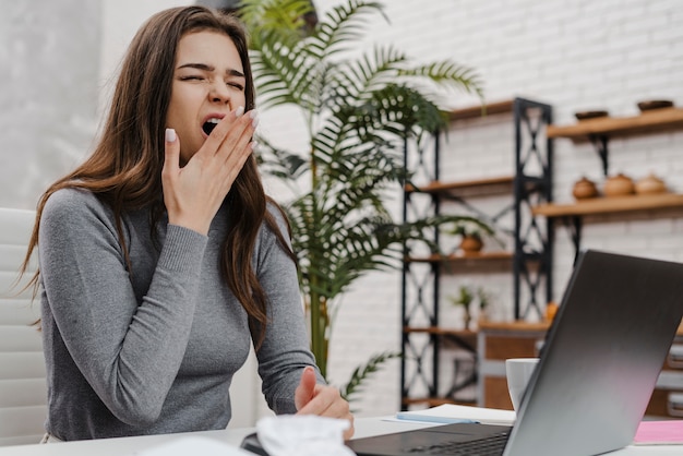 Foto jonge vrouw verveeld tijdens het werken vanuit huis